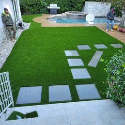 Turf with square pavers next to a spa